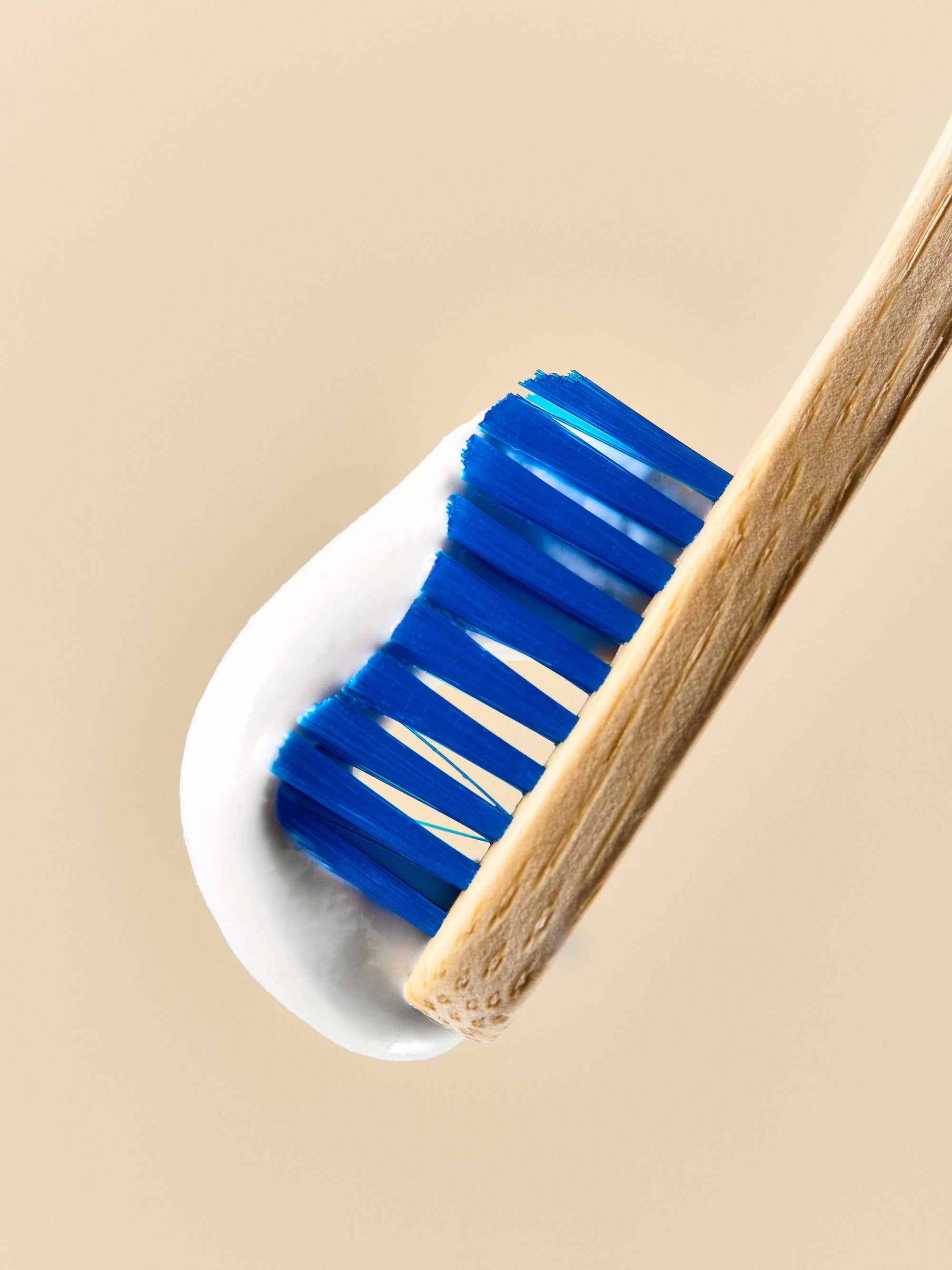 This image features a close-up view of a child's natural toothpaste in a jar, with the toothpaste applied to a toothbrush. The toothpaste is presented in a clear glass jar and appears creamy white in color, with a natural strawberry flavor.