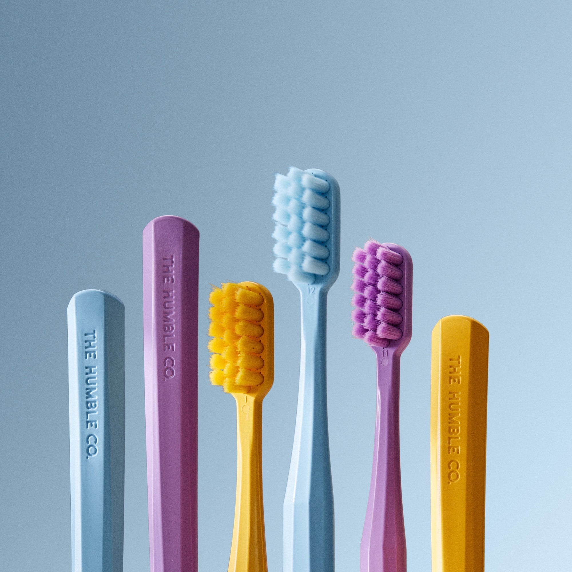Set of colorful toothbrushes from The Humble Co. on a light blue background