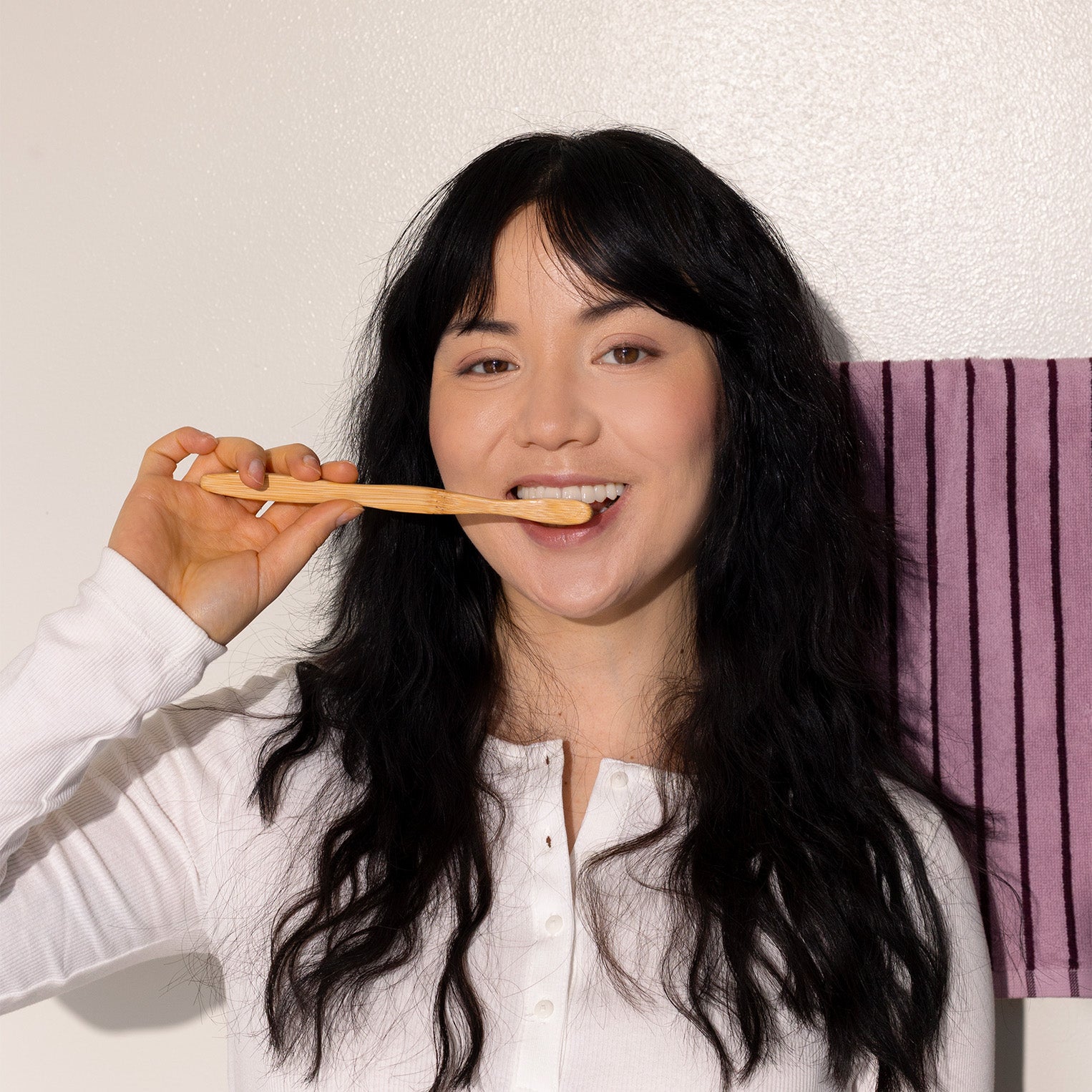 Person holding a wooden toothbrush against a plain background