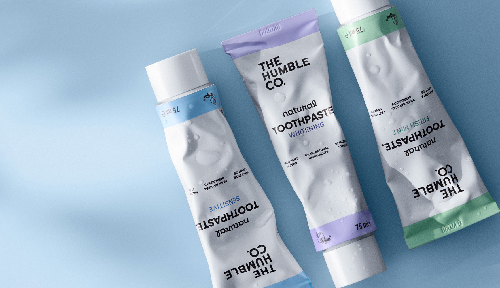 Three tubes of The Humble Co. toothpaste on a light blue background