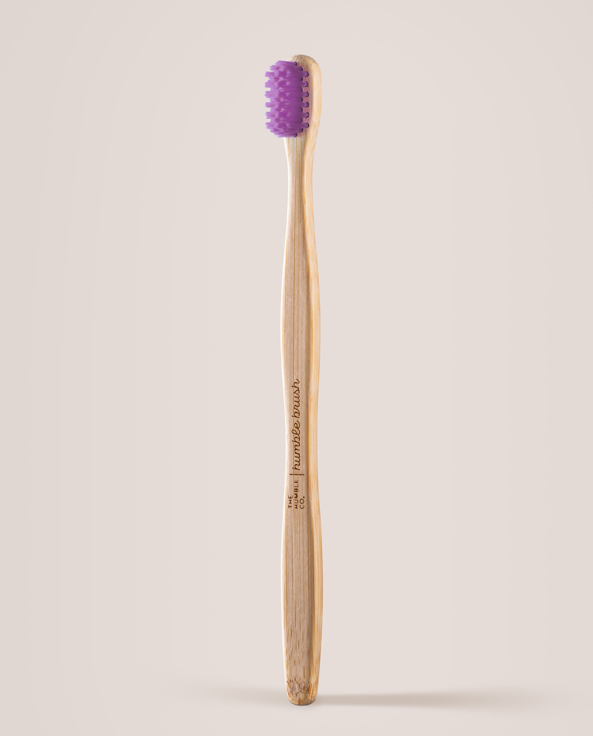 Bamboo toothbrush with purple bristles on a beige background