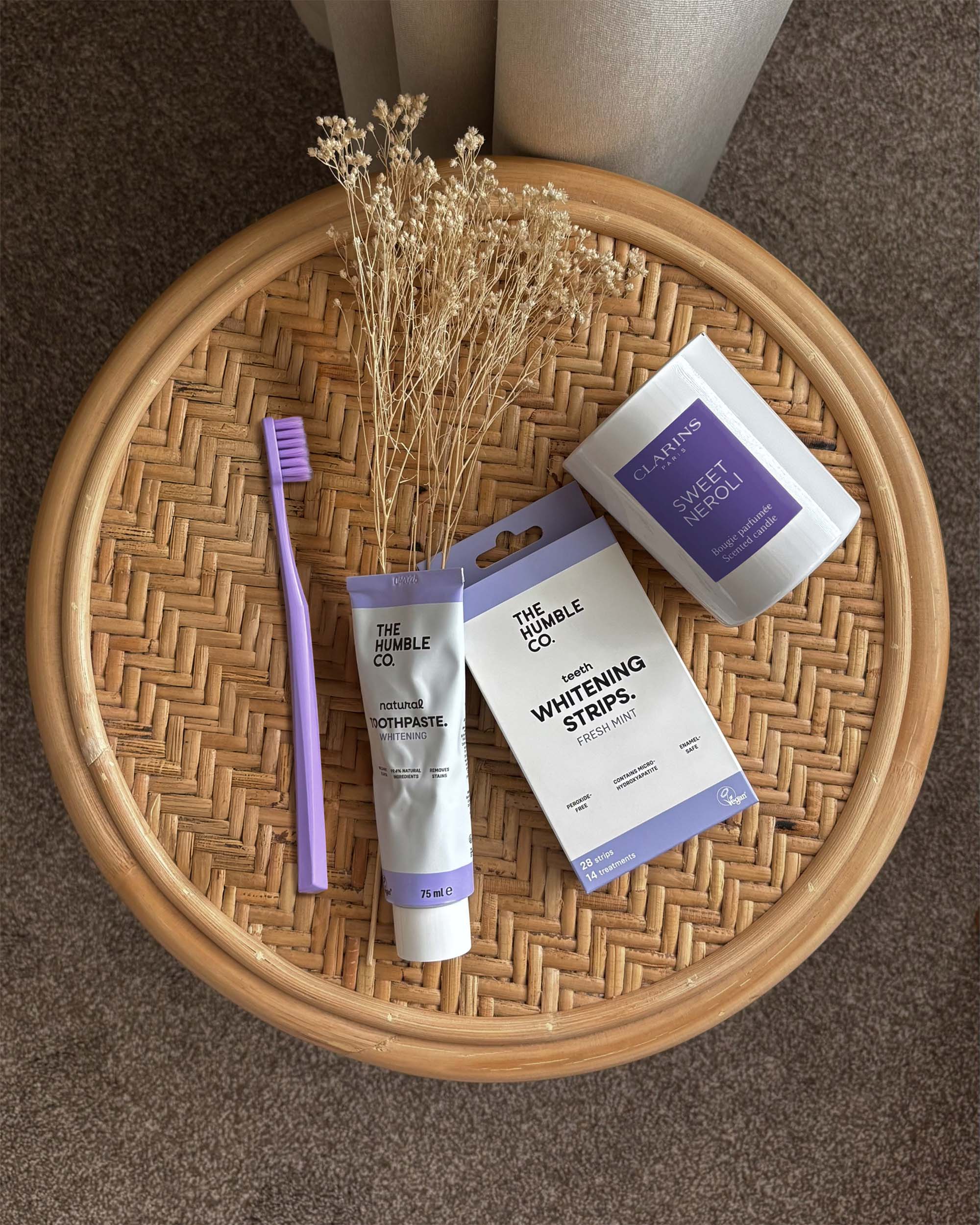 Toothbrush, toothpaste and whitening strips  on a woven tray.