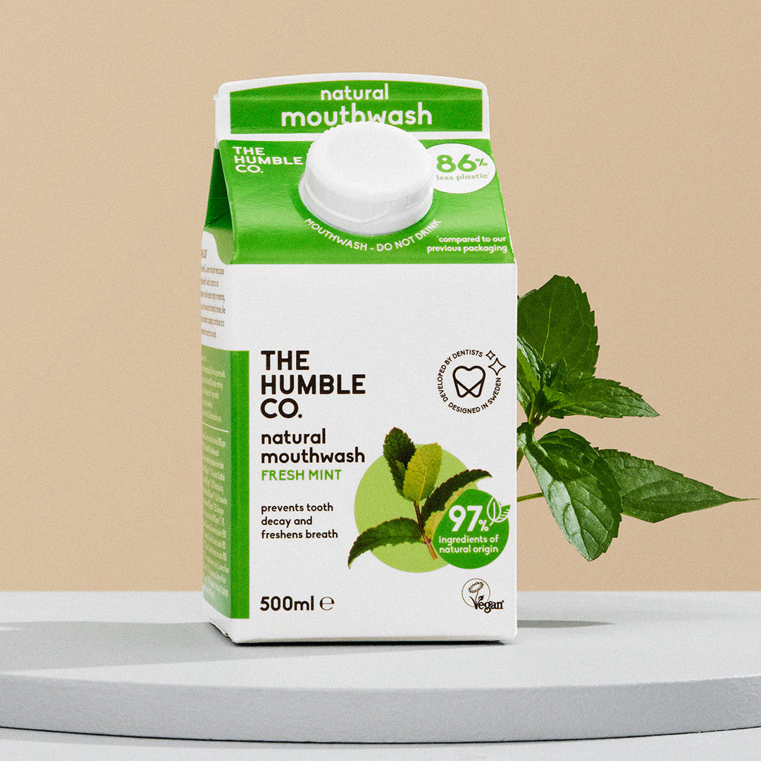 The Humble Co. natural mouthwash packaging with mint leaves on a beige background