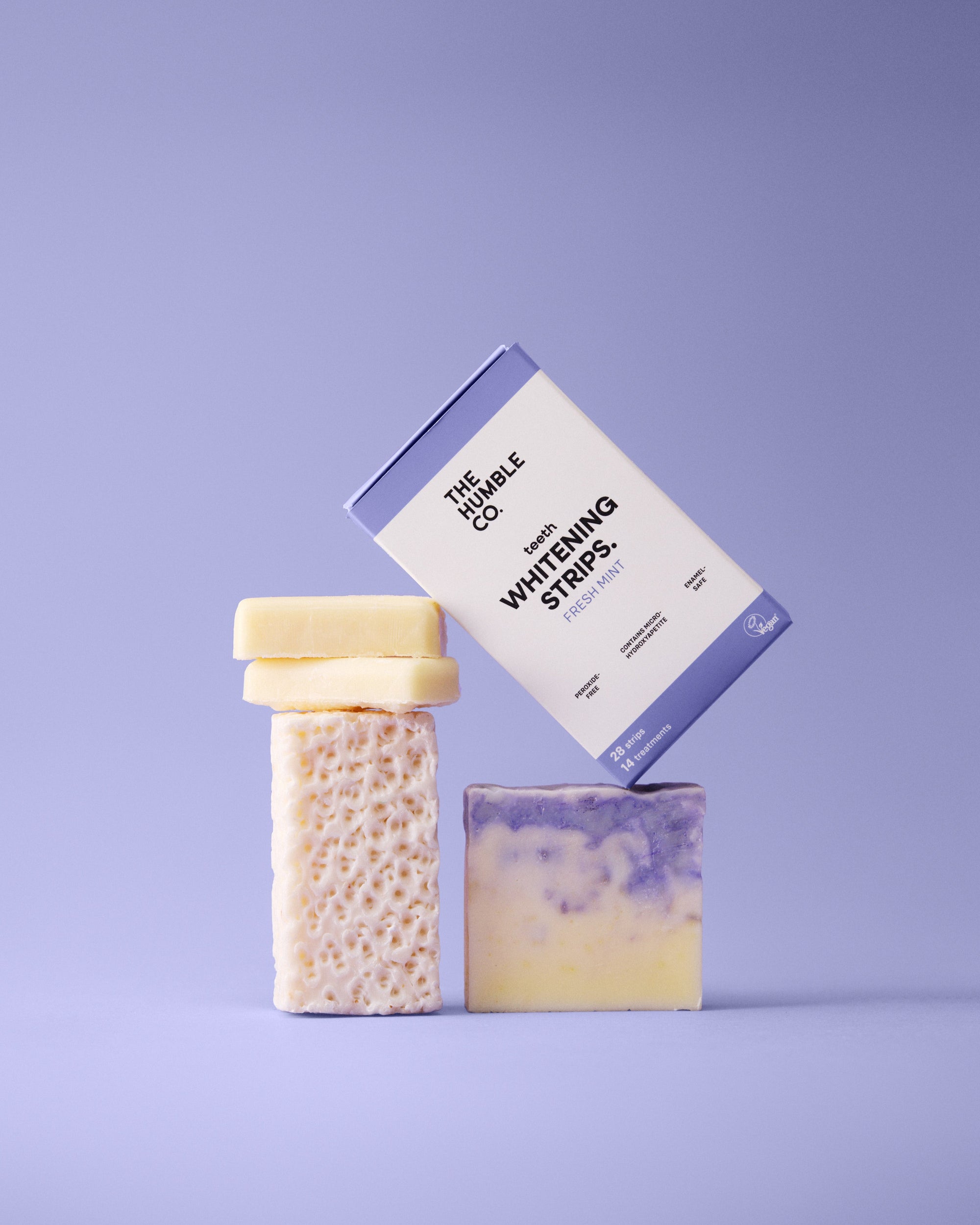 Three soaps with a box labeled 'Whiteing Strips' on a purple background