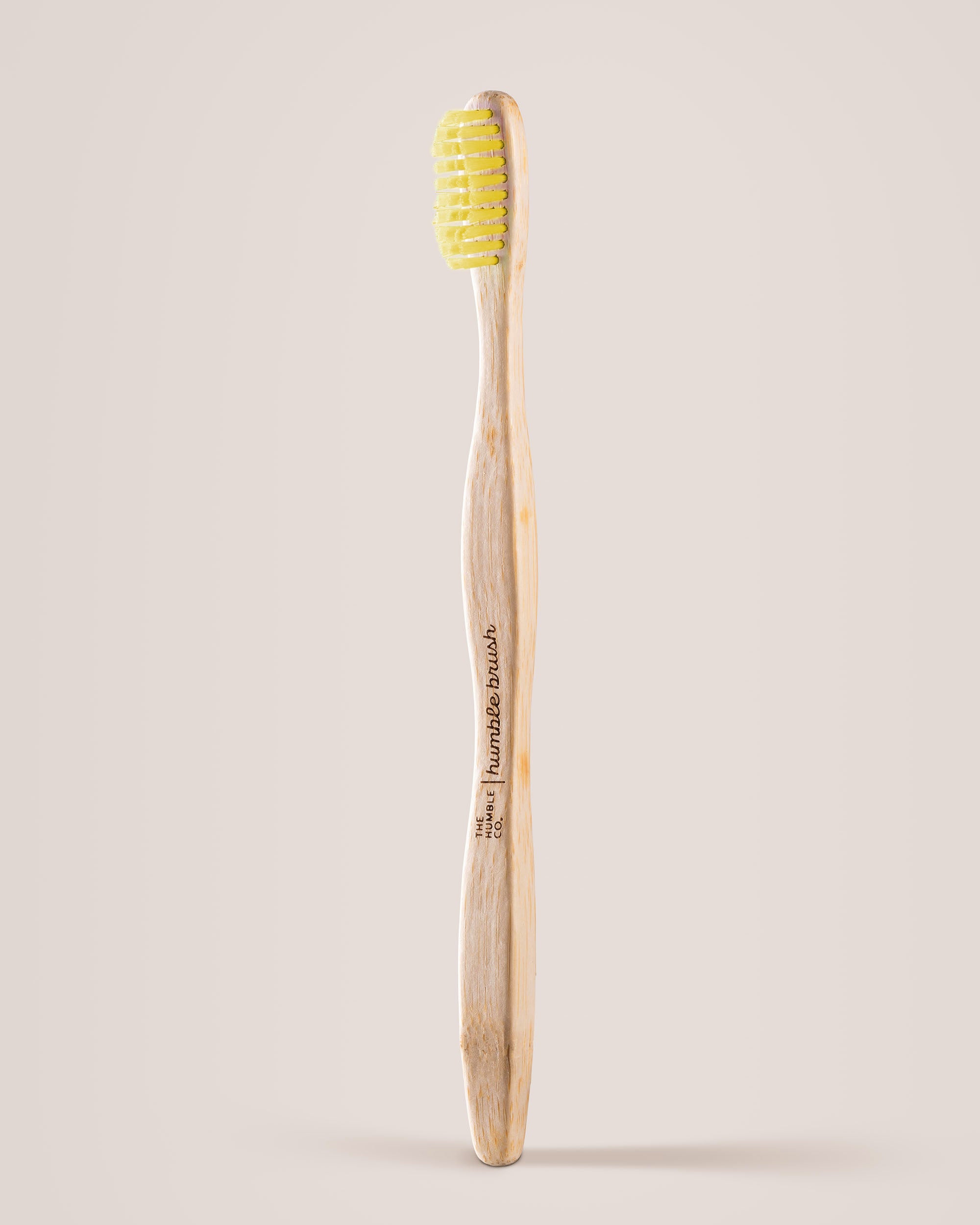 Bamboo toothbrush with yellow bristles on a beige background