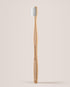 Bamboo toothbrush with white bristles on a light beige background