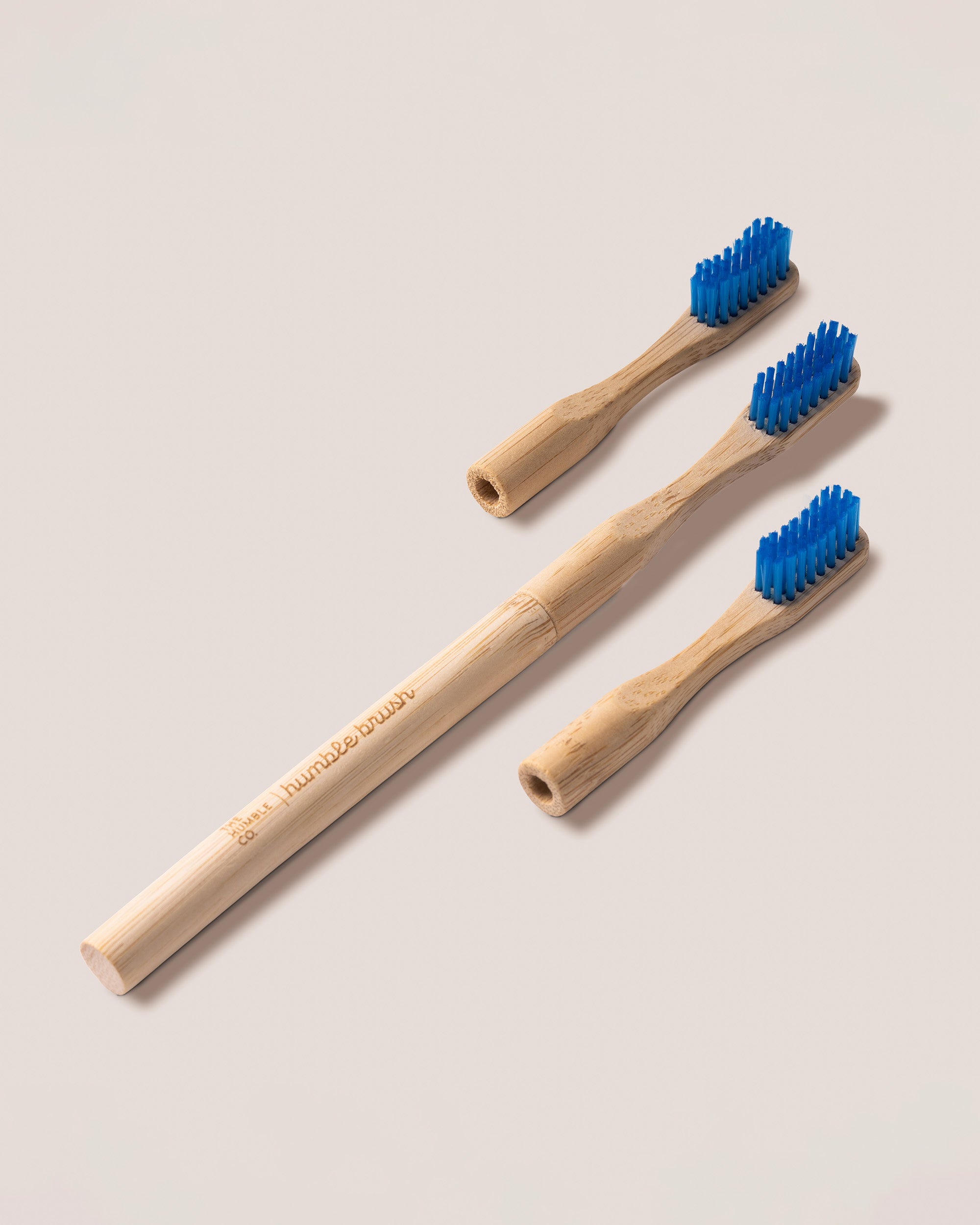 Replaceable heads bamboo toothbrushes with blue bristles on a light gray background