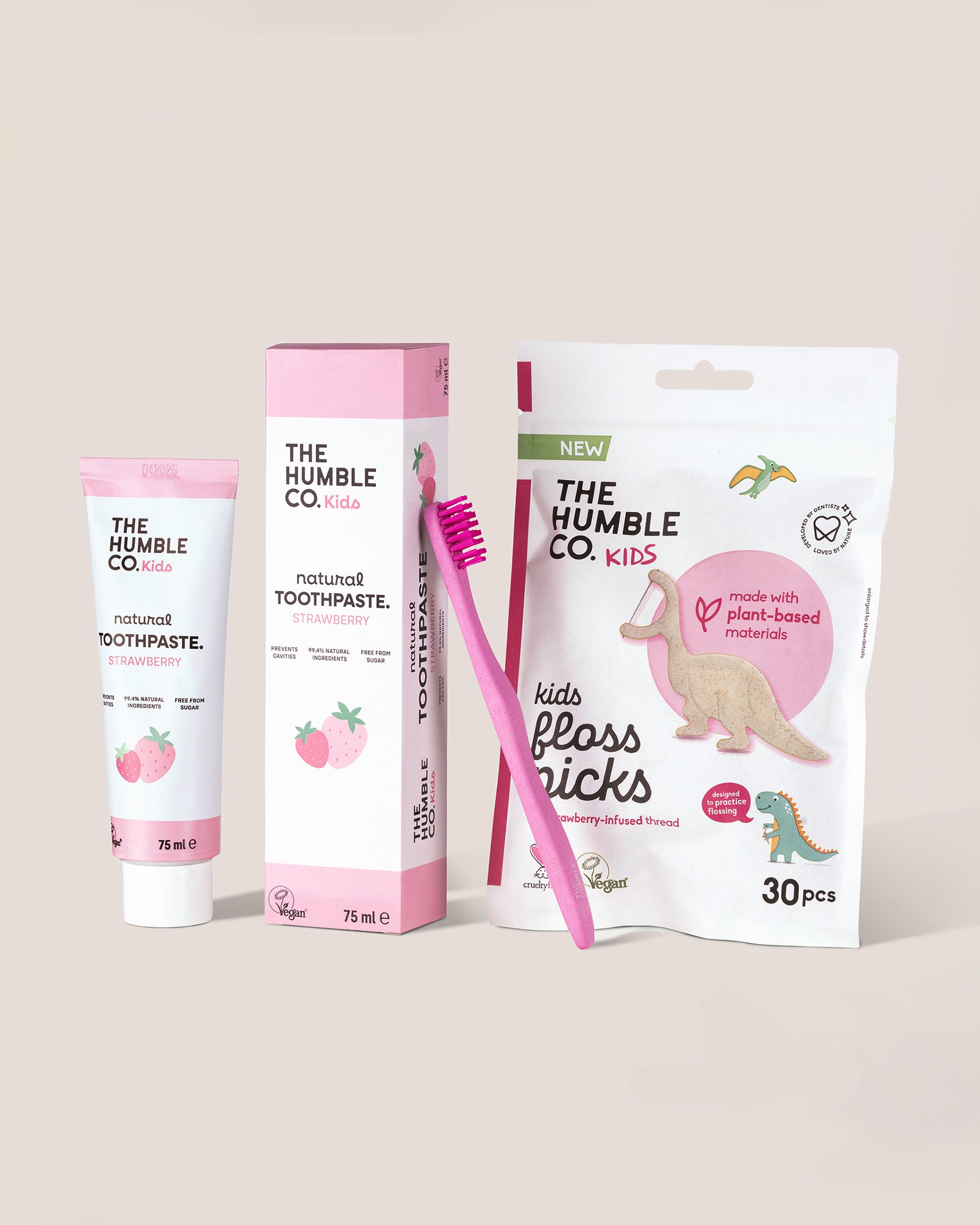 The Humble Co. dental care products including toothpaste, box, toothbrush, and floss picks on a light background
