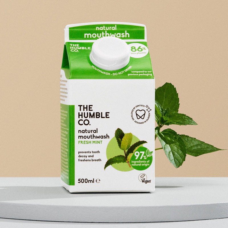 The Humble Co. natural mouthwash packaging with mint leaves on a beige background