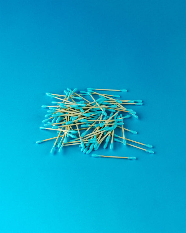 Blue cotton swabs in a stacked arrangementwith a blue background.