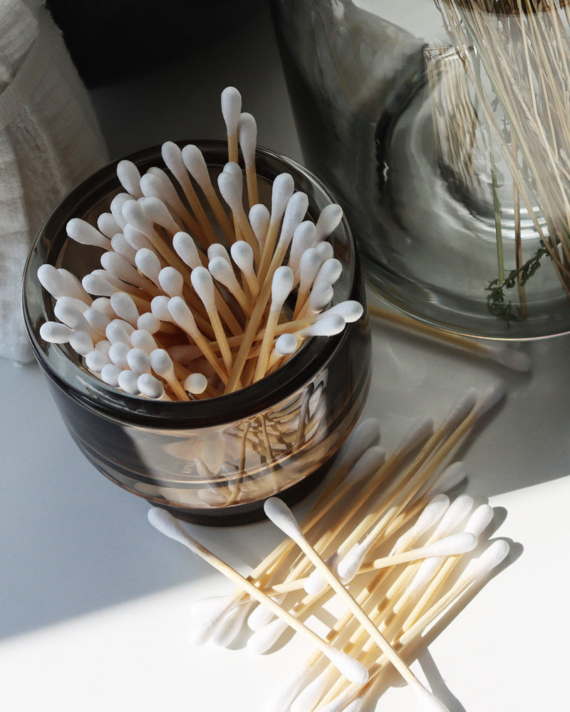 A bowl of cotton swabs in a peaceful arrangement next to a vase, representing everyday essentials.