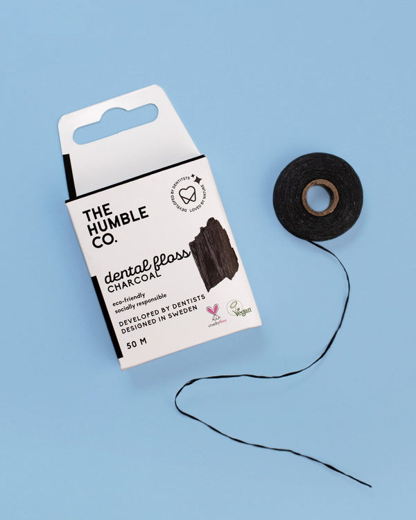 The Humble Co. Charcoal Dental Floss on a blue background, featuring a sleek design and, eco-friendly packaging